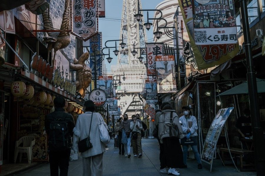 Visitors walk past restaurants in the Shinsekai shopping district of Osaka, Japan, on 29 November 2020. (Soichiro Koriyama/Bloomberg)