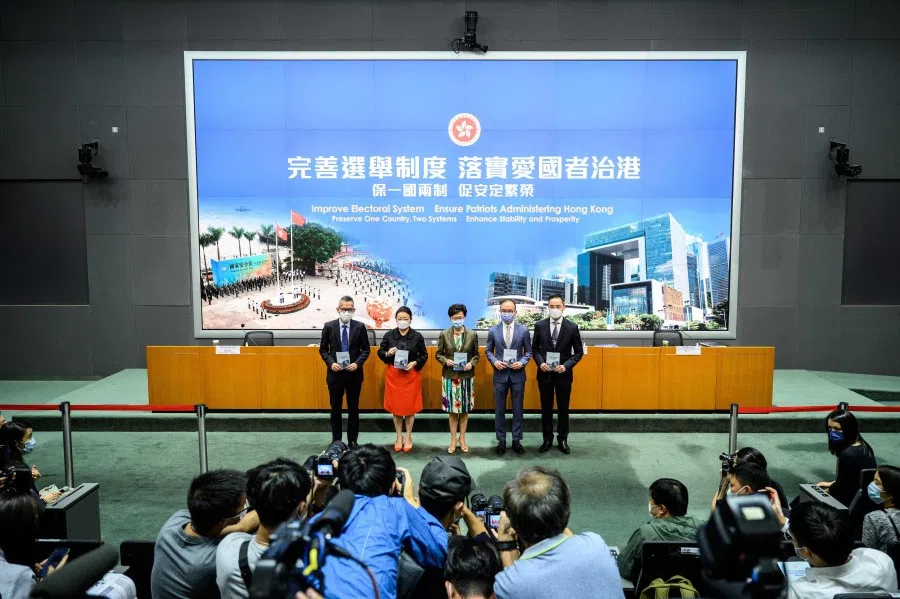 Members of the media (bottom) take photos as (left to right) Acting Law Officer (Special Duties) Llewellyn Mui, Secretary for Justice Teresa Cheng, Hong Kong's Chief Executive Carrie Lam, Secretary for Constitutional and Mainland Affairs Erick Tsang and Permanent Secretary for Constitutional and Mainland Affairs Roy Tang arrive for a press conference at the government headquarters in Hong Kong on 13 April 2021. (Anthony Wallace/AFP)