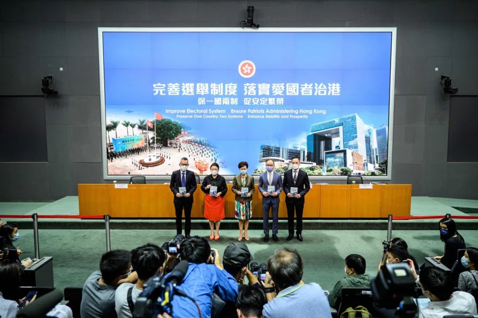 Members of the media (bottom) take photos as (left to right) Acting Law Officer (Special Duties) Llewellyn Mui, Secretary for Justice Teresa Cheng, Hong Kong's Chief Executive Carrie Lam, Secretary for Constitutional and Mainland Affairs Erick Tsang and Permanent Secretary for Constitutional and Mainland Affairs Roy Tang arrive for a press conference at the government headquarters in Hong Kong on 13 April 2021. (Anthony Wallace/AFP)