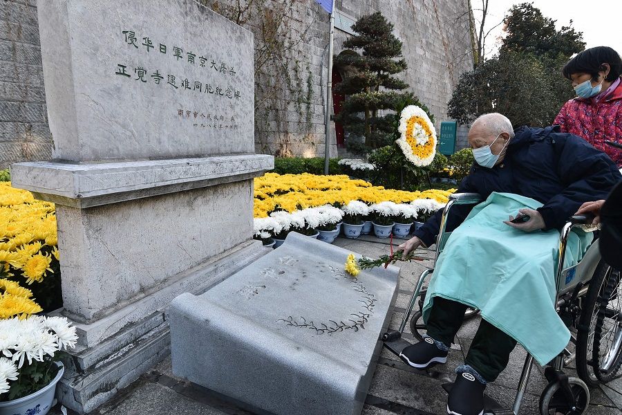 A survivor of the Nanjing Massacre places a flower in front of a memorial to mark China's National Memorial Day for Nanjing Massacre victims in Nanjing, Jiangsu province, China, on 13 December 2021. (AFP)