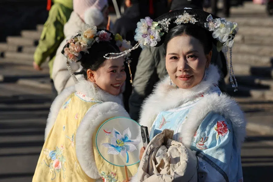 Traditionally dressed Chinese women pose for pictures in Beijing on 2 December 2025.  (Ludovic Marin/AFP)