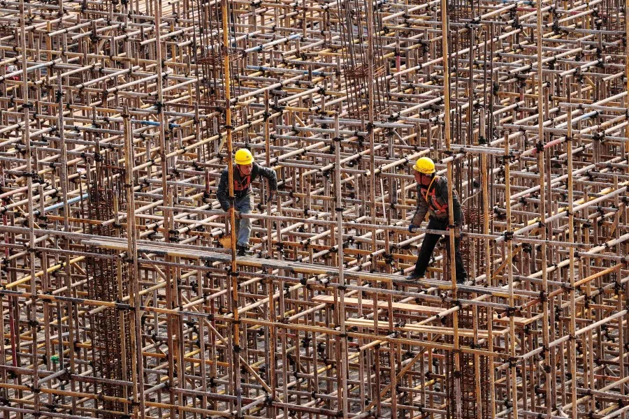 Workers are seen on scaffolding at a railway station construction site in southwestern China's Chongqing municipality on 18 February 2024. (AFP)
