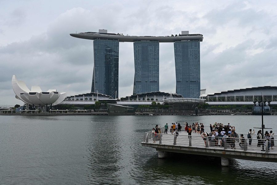 People take photographs with the backdrop of the ArtScience Museum (left) and the Marina Bay Sands resort in Singapore on 3 January 2024. (Roslan Rahman/AFP)