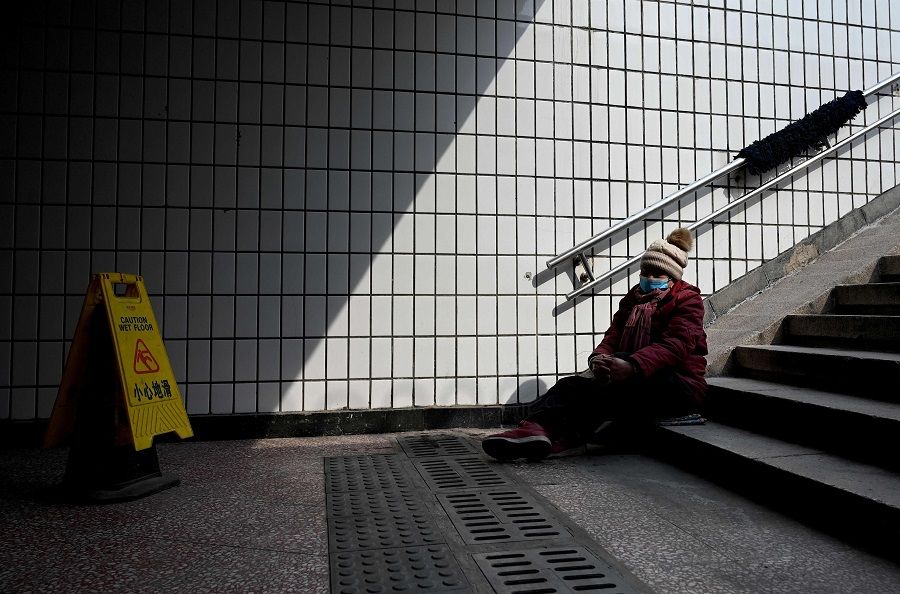 A woman rests on the steps of an underpass in Beijing, China, on 28 February 2022. (Noel Celis/AFP)
