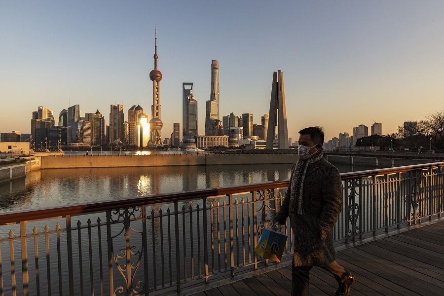 A pedestrian walks on a bridge past buildings in the Lujiazui Financial District across the Huangpu River in Shanghai, China, on 28 December 2021. (Qilai Shen/Bloomberg)