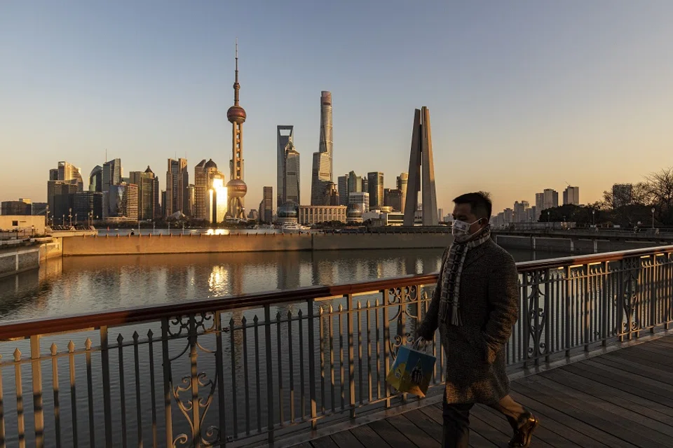 A pedestrian walks on a bridge past buildings in the Lujiazui Financial District across the Huangpu River in Shanghai, China, on 28 December 2021. (Qilai Shen/Bloomberg)