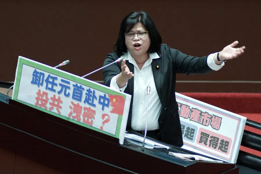 Wang Mei-hui, legislator from the ruling Democratic Progressive Party (DPP), displays a placard reading "former president visit China" and questions Premier Chen Chien-jen (not pictured) at the Parliament in Taipei on 21 March 2023. (Sam Yeh/AFP)