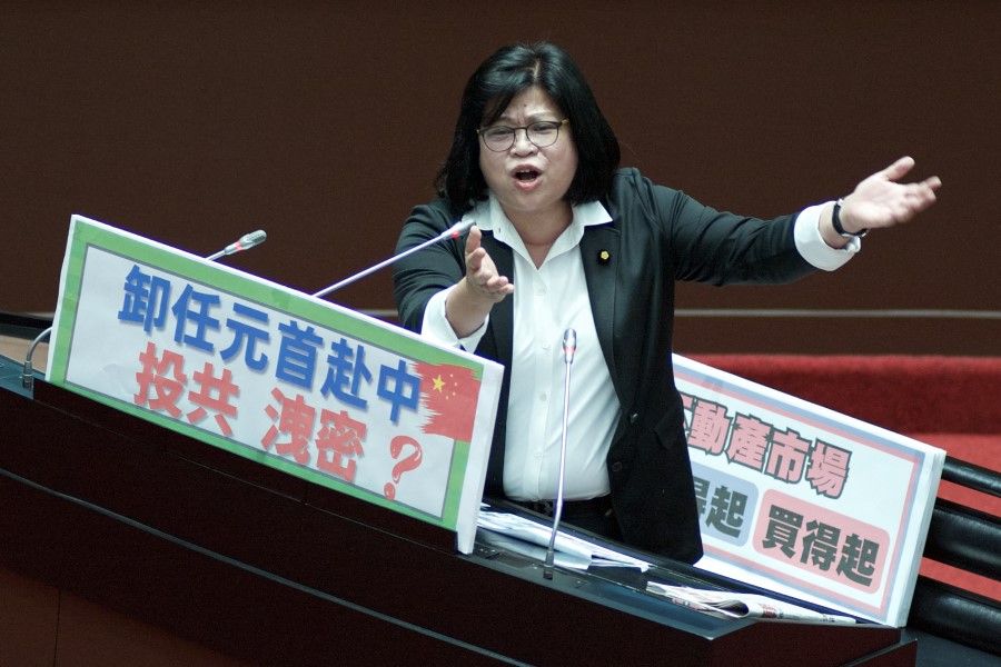 Wang Mei-hui, legislator from the ruling Democratic Progressive Party (DPP), displays a placard reading "former president visit China" and questions Premier Chen Chien-jen (not pictured) at the Parliament in Taipei on 21 March 2023. (Sam Yeh/AFP)
