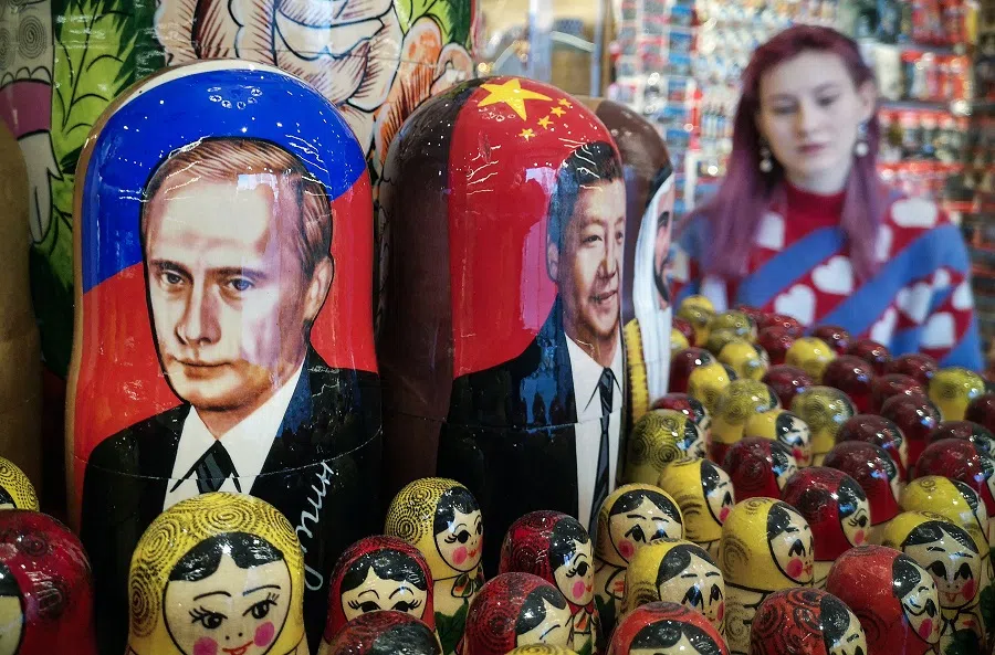 A vendor stands next to traditional Russian wooden nesting dolls depicting Russian President Vladimir Putin (left) and his Chinese counterpart Xi Jinping (centre) at a gift shop in Moscow on 11 March 2024.