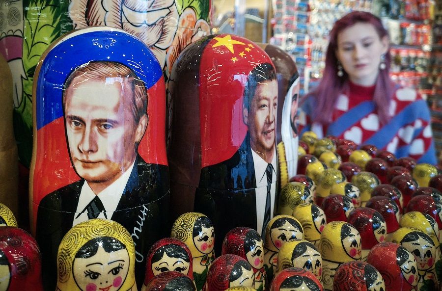 A vendor stands next to traditional Russian wooden nesting dolls depicting Russian President Vladimir Putin (left) and his Chinese counterpart Xi Jinping (centre) at a gift shop in Moscow on 11 March 2024. (Alexander Nemenov/AFP)