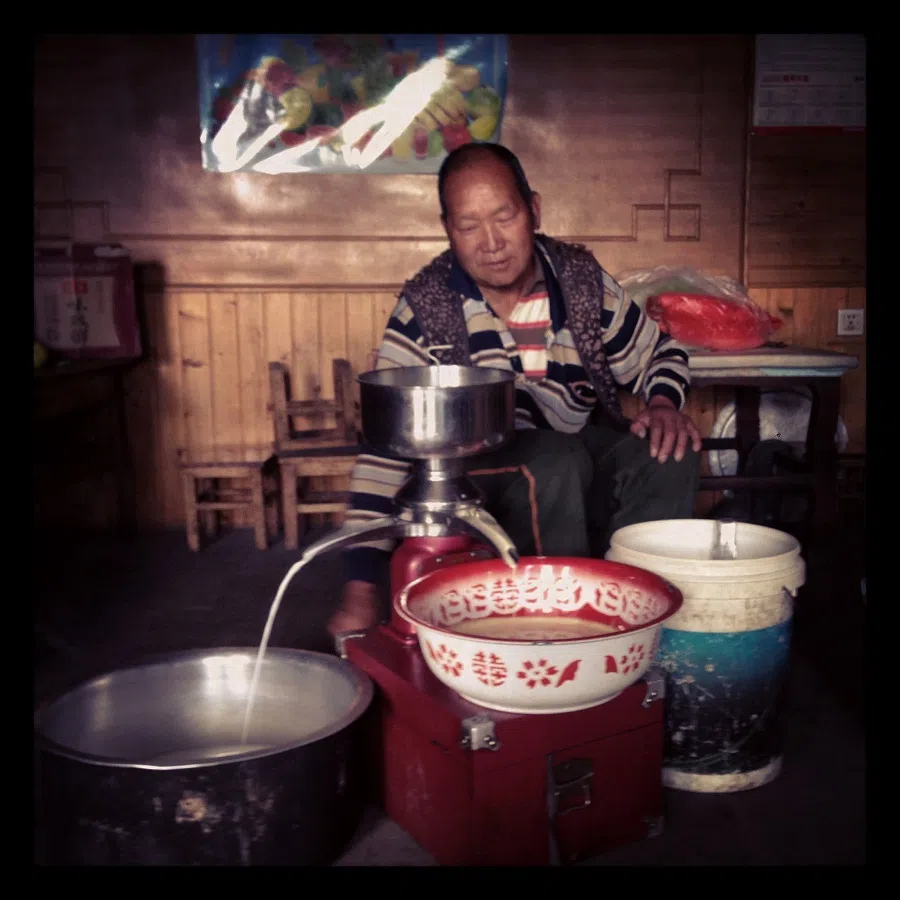 A member of a yak herding family outside of Lijiang (丽江) separating fat from yak milk.
