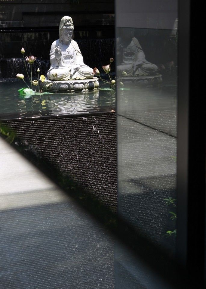 A stone carving of the Goddess of Mercy in a reflection pool. (SPH)