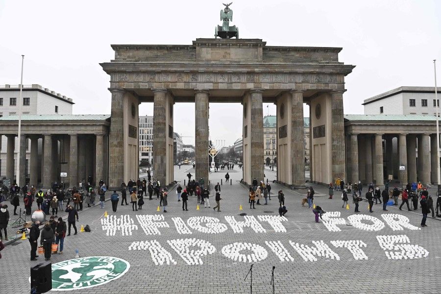 Activists of Fridays for Future finish an installation reading "#FightFor1Point5" in front of landmark Brandenburg Gate in Berlin on 11 December 2020, to mark the 5th anniversary of the Paris climate agreement. (Tobias Schwarz/AFP)