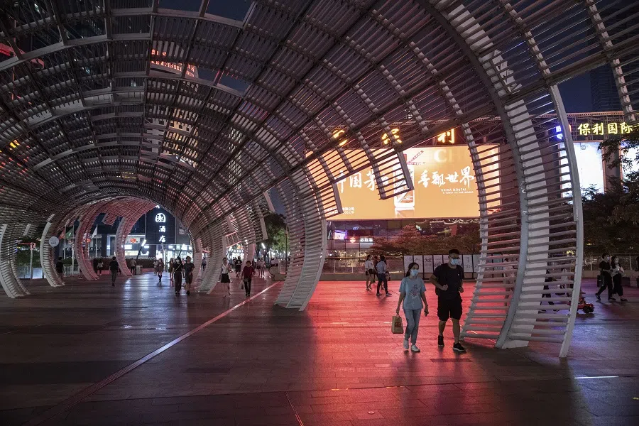 Pedestrians pass underneath a light sculpture at night in Shenzhen, China, on 30 September 2021. (Gilles Sabrie/Bloomberg)