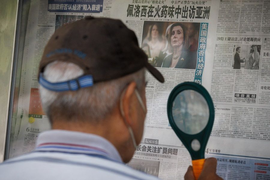 A man reads a newspaper that features a front page article about US House of Representatives Speaker Nancy Pelosi's Asia tour at a street display wall in Beijing, China, 1 August 2022. The front page headline reads: "Pelosi visits Asia in the smell of gunpowder." (Thomas Peter/Reuters)