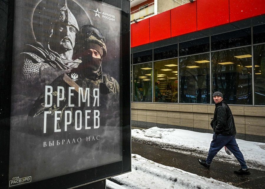 A pedestrian walks past a social advertisement billboard showing a Russian soldier in front of his ancient predecessor and reading "The Time of Heroes Has Chosen Us" displayed on a street in Moscow, Russia, on 15 February 2023. (Yuri Kadobnov/AFP)