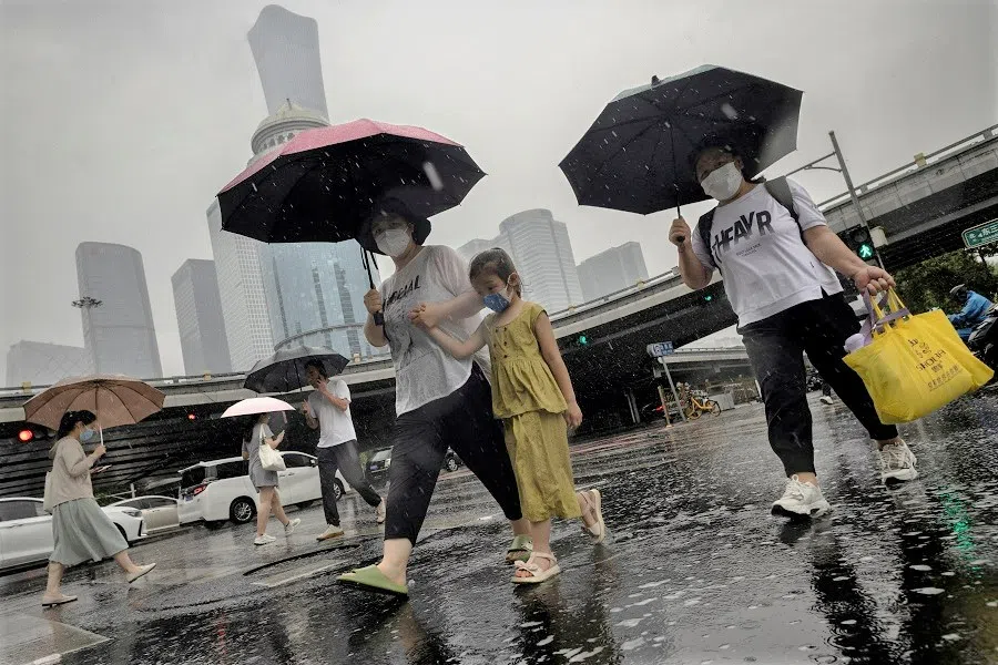 People walk in the central business district on a rainy day, in Beijing, China, on 12 July 2023. (Thomas Peter/File Photo/Reuters)