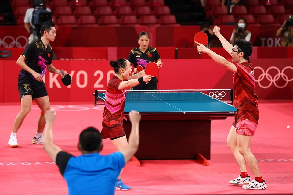 Mima Ito and Jun Mizutani of Japan celebrate winning their match against Xu Xin and Liu Shiwen of China, Tokyo Olympics, 26 July 2021. (Thomas Peter/Reuters)