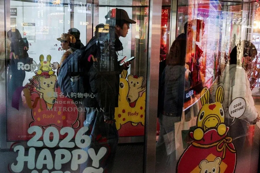 People walk through a revolving door to enter a shopping mall in Shanghai, China, on 28 February 2026. (Go Nakamura/Reuters)