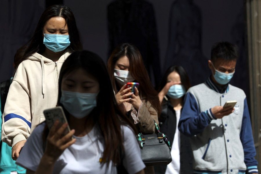 People wearing face masks walk out of a subway station during morning rush hour in Beijing, China, 26 April 2022. (Tingshu Wang/Reuters)