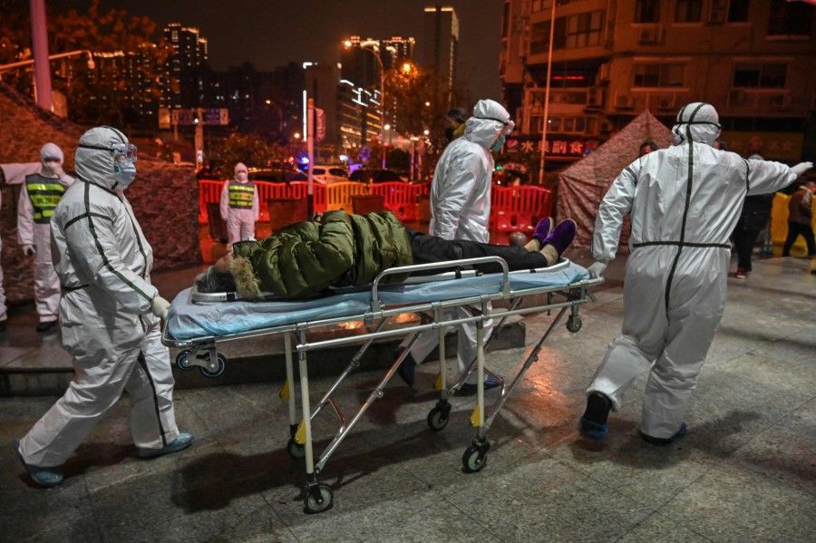 In this file photo taken on 25 January 2020, medical staff members wearing protective clothing to help stop the spread of a deadly virus which began in the city arrive with a patient at the Wuhan Red Cross Hospital in Wuhan. (Hector Retamal/AFP)