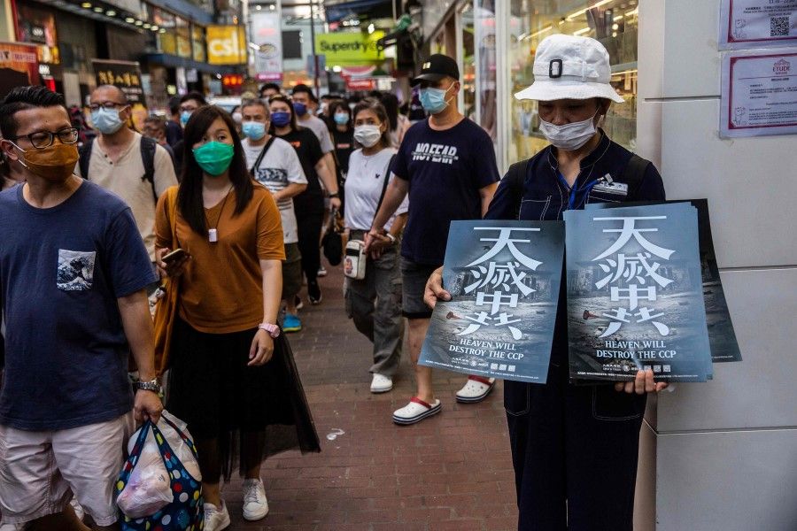 A woman (R) holds pro-democracy posters after a protest against China's national security law in Hong Kong, 28 June 2020. (Isaac Lawrence/AFP)