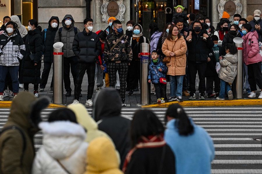 People wait to cross a street on the Bund in the Huangpu district in Shanghai, China, on 16 January 2023. (Hector Retamal/AFP)