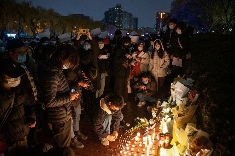 Demonstrators light candles for the victims of a deadly fire in the city of Urumqi during a protest in Beijing, China, on 27 November 2022. (Bloomberg)