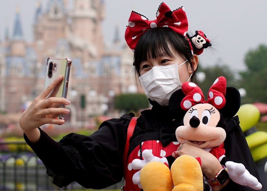 A visitor dressed as a Disney character takes a selfie while wearing a protective face mask at Shanghai Disney Resort in Shanghai, China, 11 May 2020. (Aly Song/File Photo/Reuters)