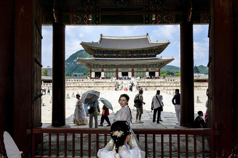 A woman wearing a traditional hanbok dress poses for photos at the Gyeongbokgung Palace in Seoul on 19 August 2024. (Anthony Wallace/AFP)