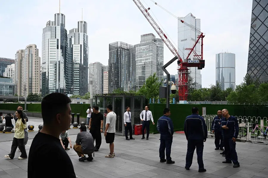 People stand outside buildings in Beijing’s central business district on 31 July 2025. (Greg Baker/AFP)