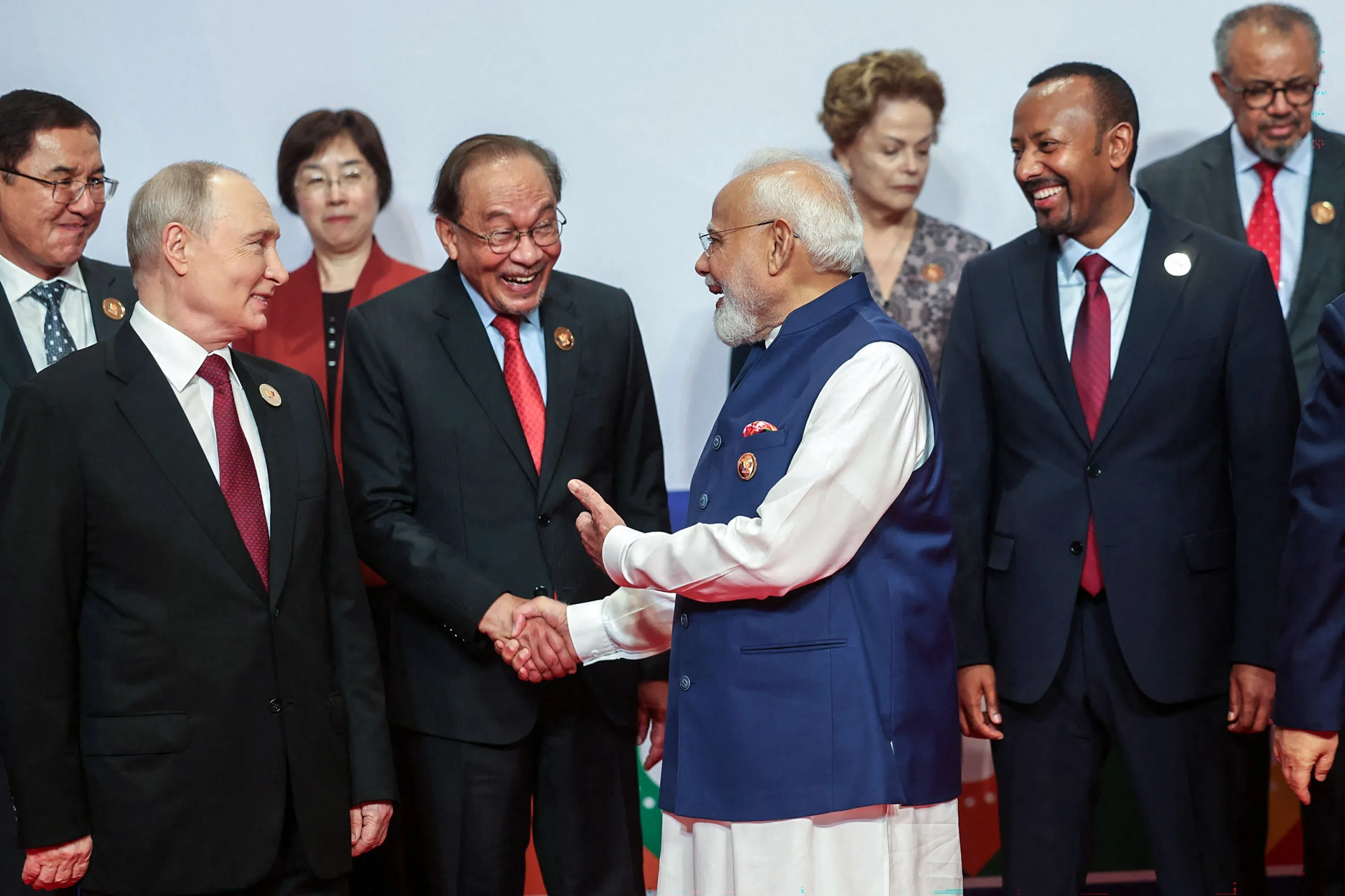 This handout photograph taken and released by India’s Press Information Bureau (PIB) on 13 September 2026 shows India's Prime Minister Narendra Modi (second from right) speaking with Malaysia’s Prime Minister Anwar Ibrahim (second from left) and Russia's President Vladimir Putin (left) during a gathering for a family photo at the 18th BRICS Summit in New Delhi.