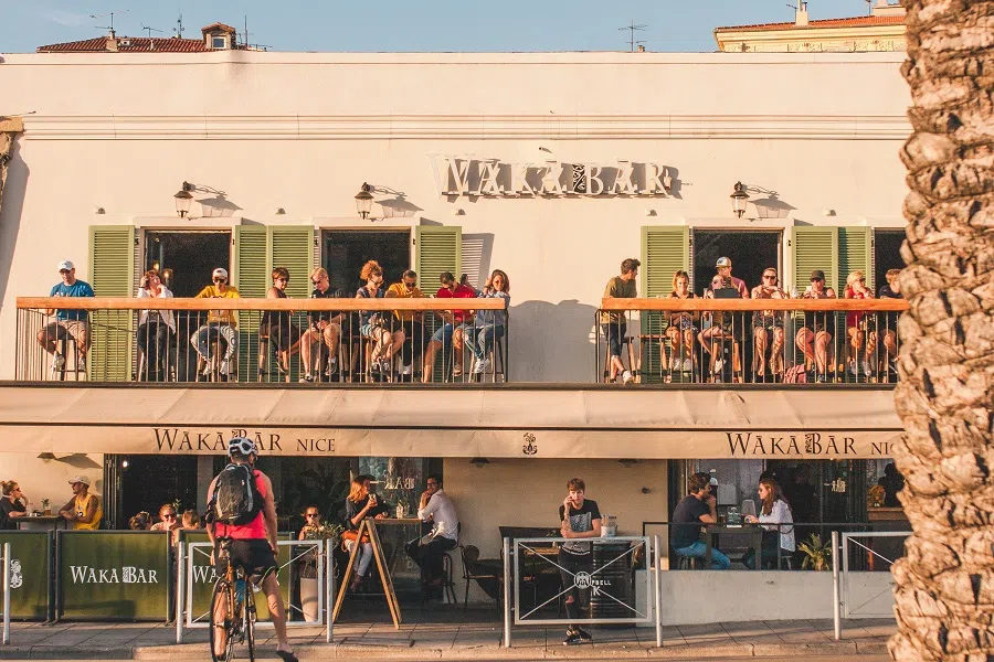 People relax on the balconies of a cafe overlooking the sea. (iStock)
