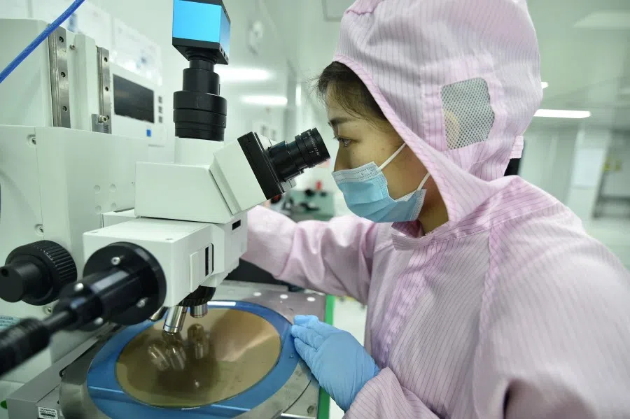 An employee inspects a wafer at the production line of a semiconductor chip company in Suqian, Jiangsu province, China, 28 February 2023. (China Daily via Reuters)