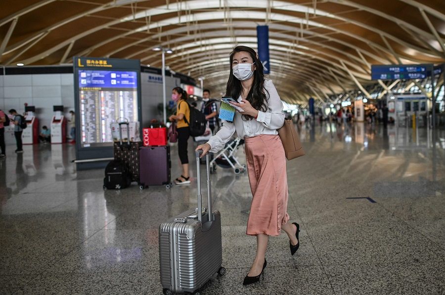 In this file photo, passengers wearing face masks are seen in Pudong International Airport in Shanghai on 11 June 2020. (Hector Retamal/AFP)