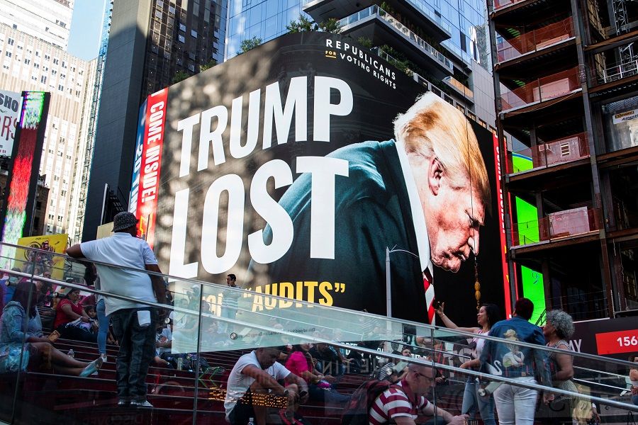 People look at a billboard showing former US President Donald Trump in Times Square in New York, US, 14 October 2021. (Eduardo Munoz/Reuters)