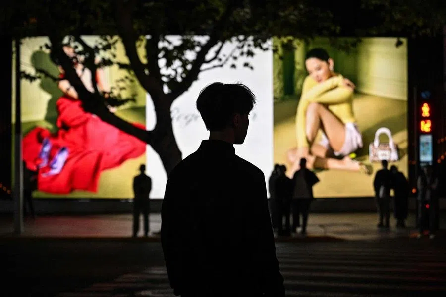People wait to cross a street in the Jing'an district in Shanghai on 10 November 2025. (Hector Retamal/AFP)