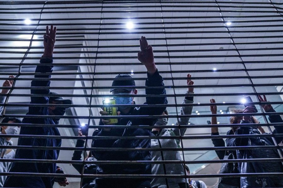 Pro-democracy demonstrators gesture with three-fingered salutes outside West Kowloon Magistrates Courts during a hearing for 47 opposition activists charged with violating the city's national security law in Hong Kong on 4 March 2021. (Lam Yik/Bloomberg)
