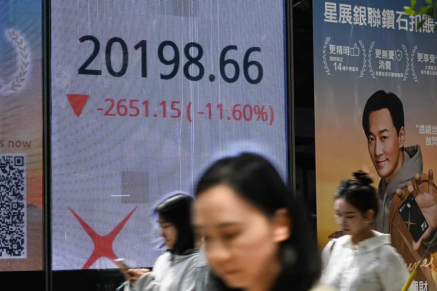 People walk past an electronic sign board showing the Hang Seng Index stocks in Hong Kong on 7 April 2025. (Peter Parks/AFP)
