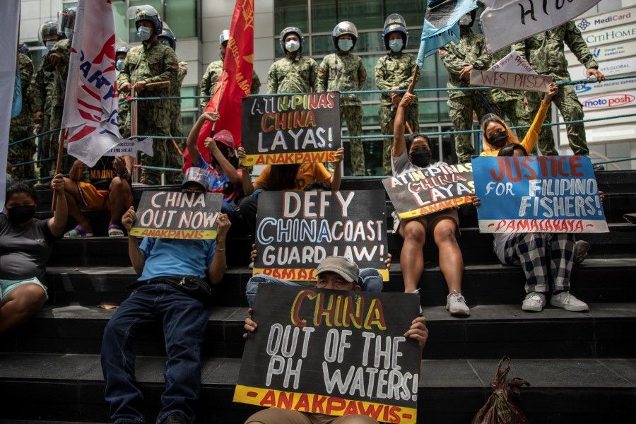 Activists stage a protest outside the Chinese Consulate, guarded by Philippine police, on the fifth anniversary of an international arbitral court ruling invalidating Beijing's historical claims over the waters of the South China Sea, in Makati City, Philippines, 12 July 2021. (Eloisa Lopez/Reuters)