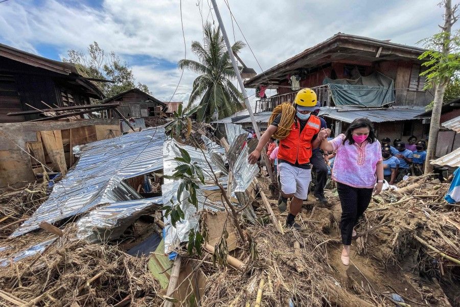 This handout photo taken on 21 December 2021 and received from the Office of the Philippine Vice President on 22 December 2021 shows Philippine Vice President Leni Robredo (right) inspecting an area hit by Super Typhoon Rai in Bais city, Negros Oriental in the central Philippines. (Handout/Office of the Philippine Vice President/AFP)