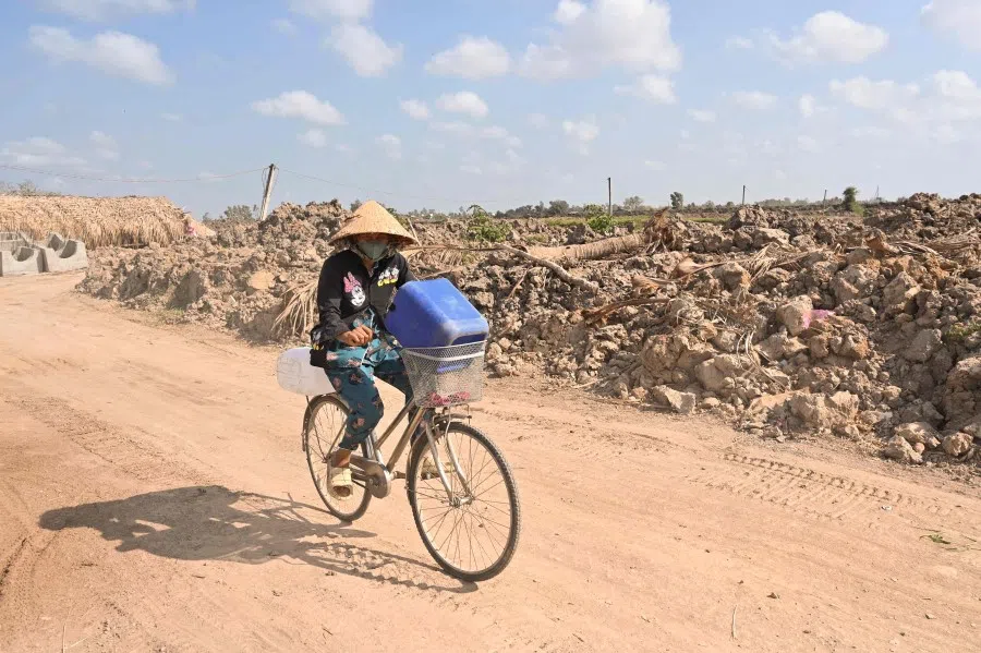 A woman rides a bicycle carrying plastic cans for fresh water, in Vietnam's southern Ben Tre province on 19 March 2024. (Nhac Nguyen/AFP)