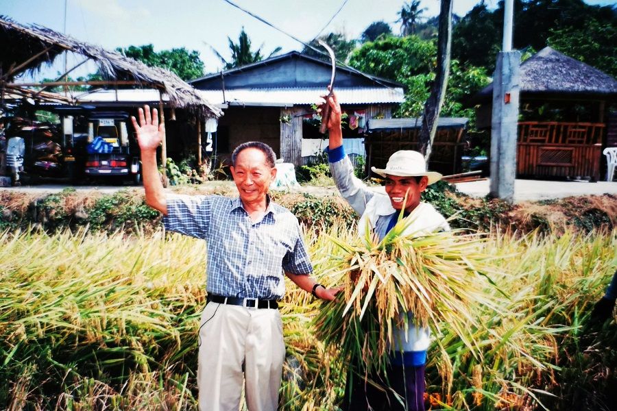 Yuan Longping (left) is seen celebrating the harvest of 'super hybrid rice' with a local farmer on his visit to the Philippines in 2003. (Photo reproduced by CNS)