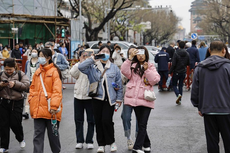 People stroll on a street near the Forbidden City in Beijing, China, on 5 April 2023. (Ludovic Marin/AFP)