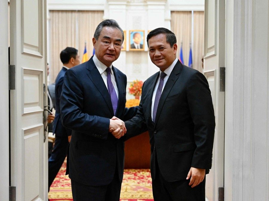 This handout photo taken and released by Cambodia's Government Cabinet on 13 August 2023 shows Cambodia's prime minister-designate Hun Manet (right) shaking hands with China's Foreign Minister Wang Yi at the Peace Palace in Phnom Penh. (Kok KY/Cambodia's Government Cabinet/AFP)