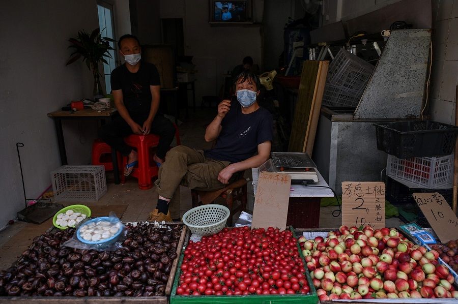 Vendors wearing face masks wait for customers in a market in Wuhan, China, on 18 May 2020. (Hector Retamal/AFP)