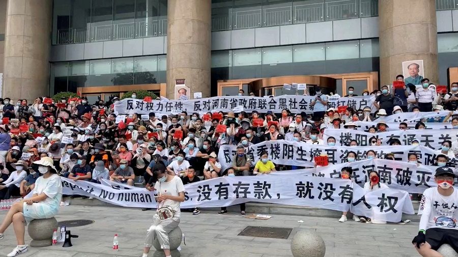 Demonstrators hold banners during a protest over the freezing of deposits by rural-based banks, outside a People's Bank of China building in Zhengzhou, Henan province, China, 10 July 2022, in this screengrab taken from video obtained by Reuters. (Handout via Reuters/File Photo)