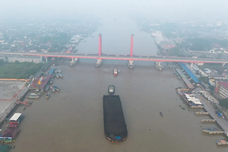 A drone view shows a tug boat pulling a coal barge along the Musi river, passing Ampera Bridge, as smog covers it due to recent wildfires in Palembang, South Sumatra province, Indonesia, on 11 August 2026.