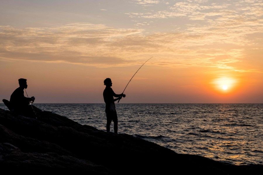 A man fishes at sunset on the Thai island of Ko Samet on 20 December 2021. (Jack Taylor/AFP)