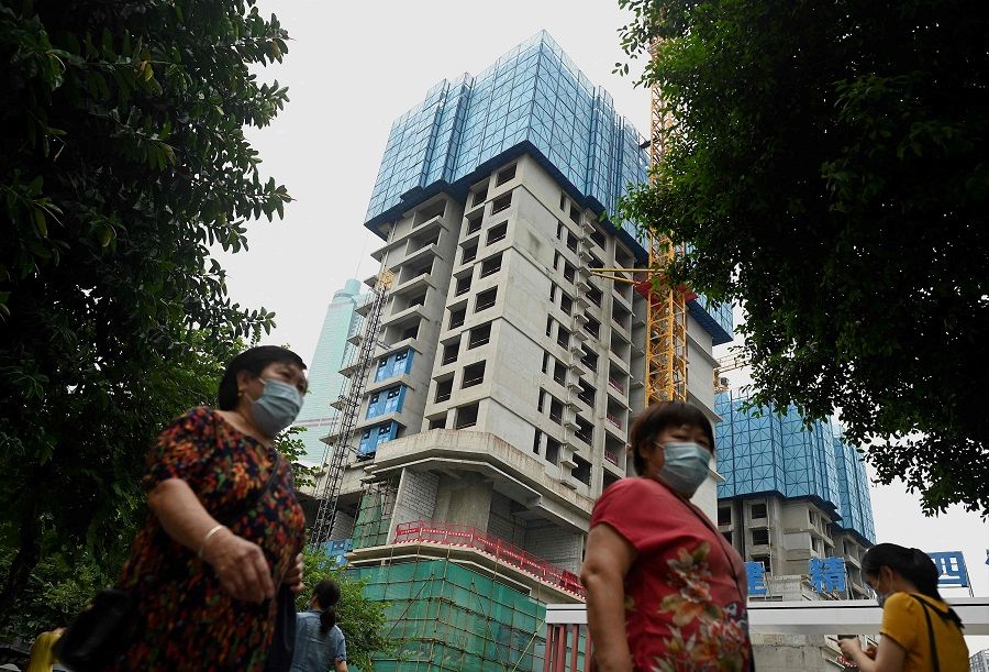 Pedestrians walk in front of an under construction Evergrande housing complex in Shenzhen, China, on 16 September 2021. (Noel Celis/AFP)